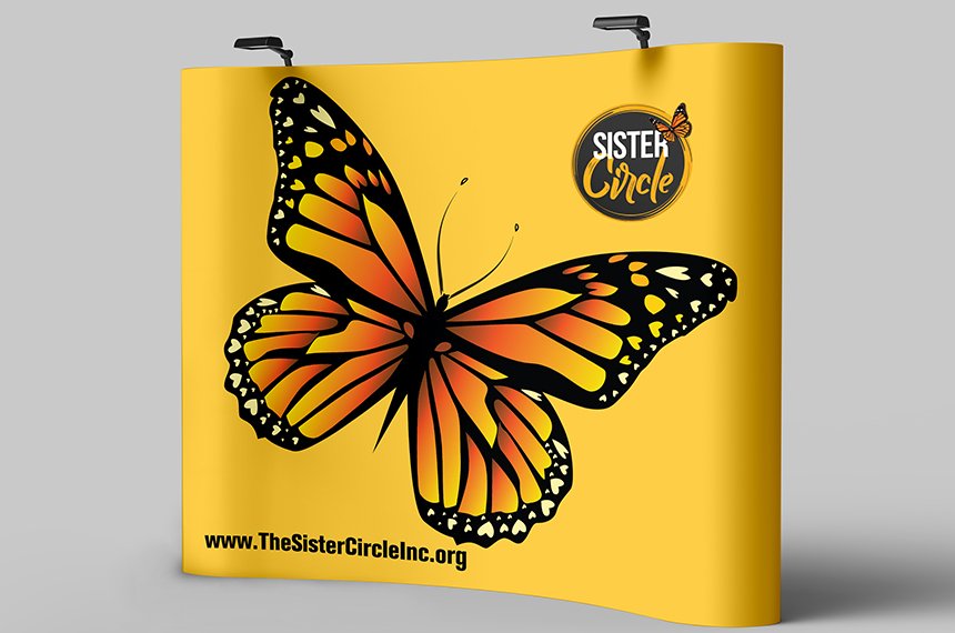 Yellow curved pop-up trade-show wall with large monarch butterfly and Sister Circle logo, designed by Rahat Abir.