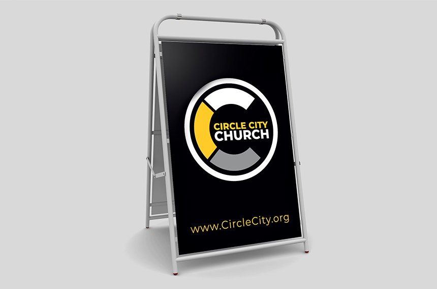 Black A-frame sidewalk sign displaying Circle City Church logo and URL, design by Rahat Abir.